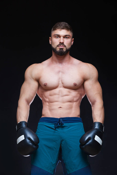 Strong muscular boxer in black boxing gloves. Isolated on black background. - Photo, image