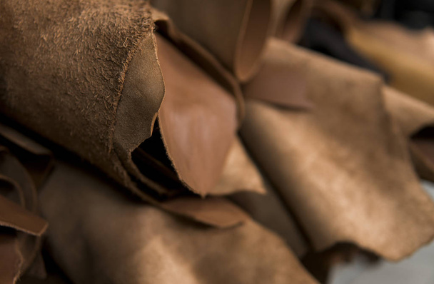 Different pieces of leather in a rolls. The pieces of the colored leathers. Rolls of natural brown red leather. Raw materials for manufacture of bags, shoes, clothing and accessories. - Valokuva, kuva