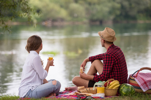 Couple in love enjoying picnic time drink and food in beautiful nature on the river bank - Valokuva, kuva