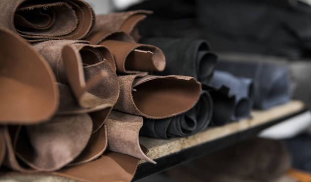Different pieces of leather in a rolls. The pieces of the colored leathers. Rolls of natural brown and black and other leather. Raw materials for manufacture of bags, shoes, clothing and accessories. - Fotoğraf, Görsel