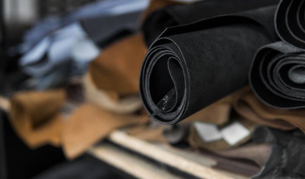 Different pieces of leather in a rolls. The pieces of the colored leathers. Rolls of natural brown and black and other leather. Raw materials for manufacture of bags, shoes, clothing and accessories. - Fotoğraf, Görsel