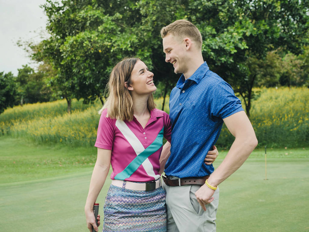 Happy golfer couple hugging together at green field outdoor. - Fotografie, Obrázek