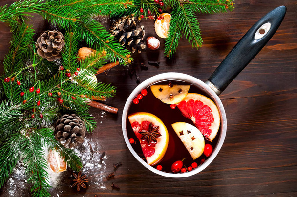 Christmas background. Hot mulled wine with ingredients in authentic ladle on wooden background. The concept of celebration and cooking warming drinks.Top view, close up, copy space - Фото, изображение