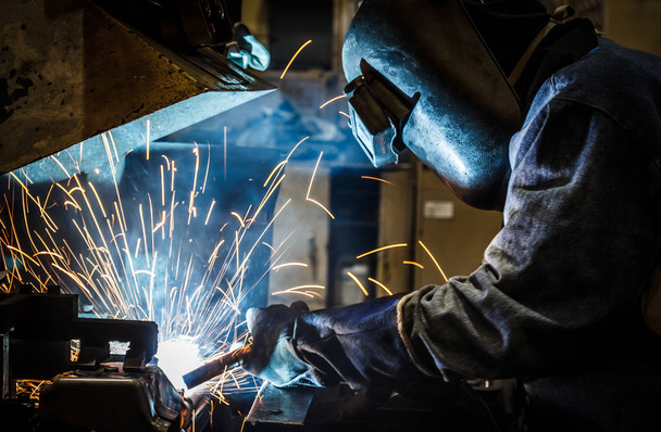 Industrial steel worker speeds motion in factory worker with protective mask welding metal - Fotoğraf, Görsel