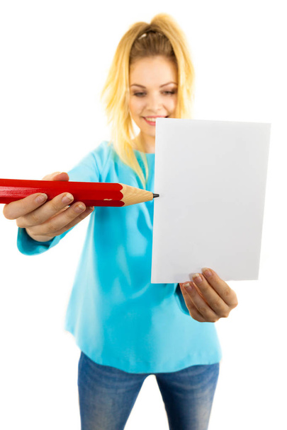 Adolescente mulher escrevendo algumas notas em pedaço de papel usando grande lápis de grandes dimensões. - Foto, Imagem