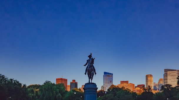 Statue von George Washington im öffentlichen Garten von Boston vor blauem Himmel und Skyline der Innenstadt in der Abenddämmerung, in Boston, USA - Foto, Bild