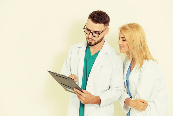 GP doctor looks at data in documents on clipboard while discussing with surgical doctor on white background. Medical service and healthcare concept. - Φωτογραφία, εικόνα