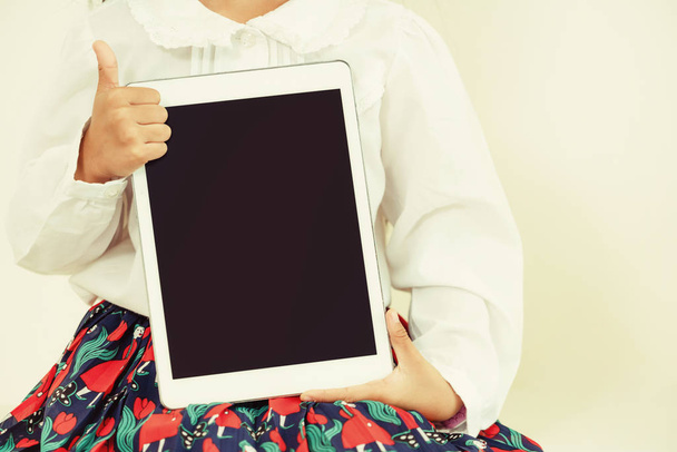 Criança mostrando tela preta do computador tablet no fundo branco
. - Foto, Imagem