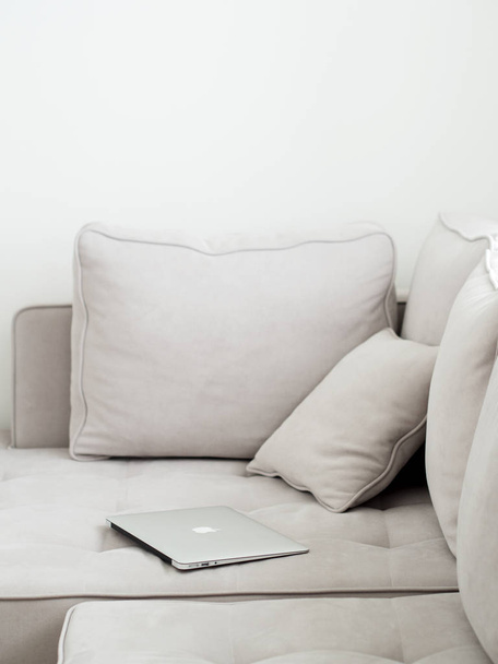Срібний ноутбук, лежить на сірому дивані, мінімалістичний стиль
  - Фото, зображення