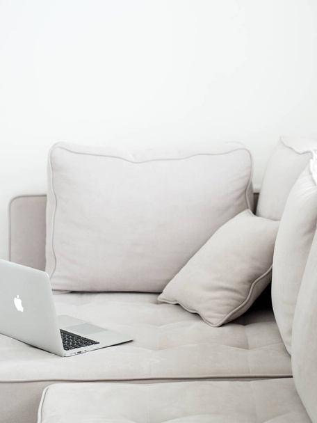 Open silver laptop lying on gray sofa, Minimalistic style  - Photo, Image