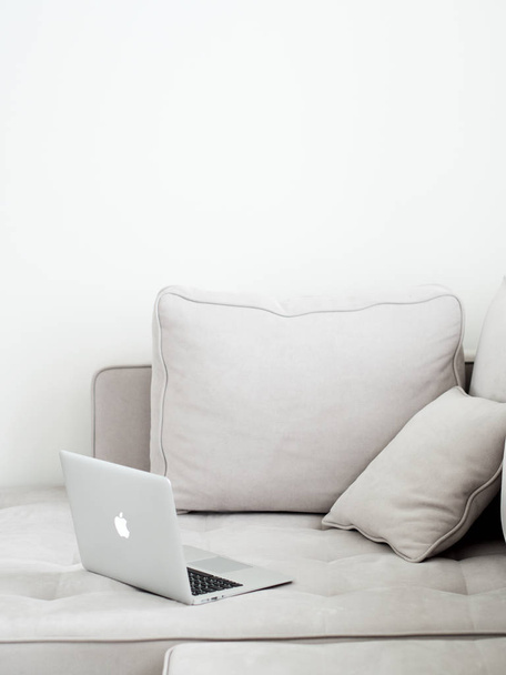 Open silver laptop lying on gray sofa, Minimalistic style  - Photo, Image