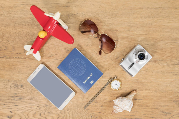 Concept time to go on vacation - toy plane, clock and passport and other items on old wooden table - Foto, Bild