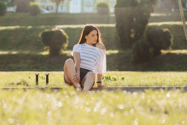 cozy fitness girl making exercises with dumbbells on sunset at grass outside - Fotoğraf, Görsel