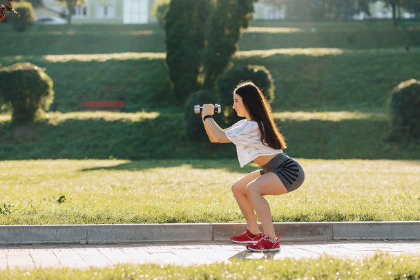 fille de fitness confortable faire des exercices avec haltères sur le coucher du soleil à l'herbe à l'extérieur
 - Photo, image