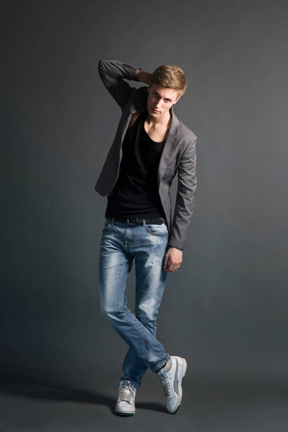 Young man in jeans and stylish blazer posing on grey background - Zdjęcie, obraz