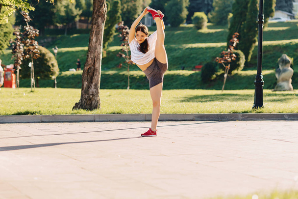 fitness cozy girl making stretching at park at morning sunshine - Foto, imagen