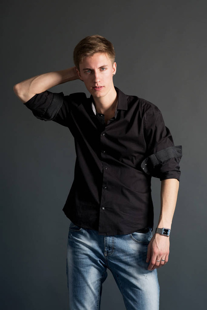 Young man in black shirt posing on black background - Foto, immagini