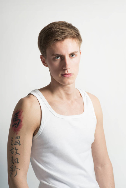 Portrait of young man in white t-shirt posing on white background - Fotó, kép