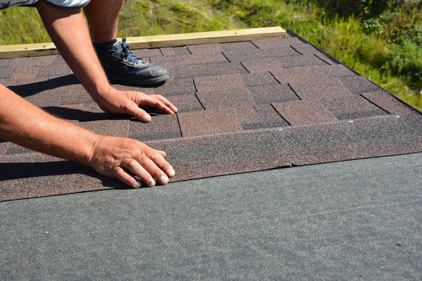Roofer hands laying Asphalt Shingles on house construction roof. Roofing construction with Asphalt Shingles.  - Fotografie, Obrázek