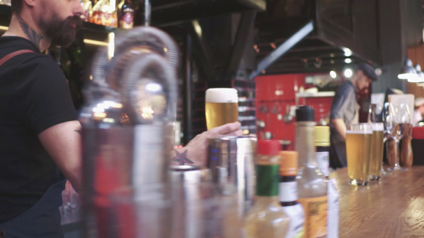 Verser de la bière fraîche. Gros plan d'un jeune barman versant de la bière debout au comptoir du bar
 - Séquence, vidéo