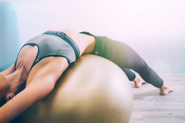 Woman working out with exercise ball in gym. Pilates woman doing exercises in the gym workout room with fitness ball. Fitness woman doing exercises for muscle press with abs swiss ball. - Photo, Image