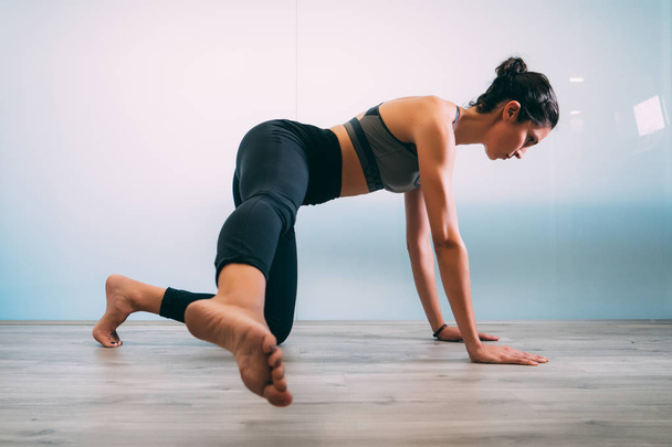 Young sporty attractive woman practicing yoga, pilates, doing Staff exercise at yoga studio, side view. Yoga and Pilates lifestyle healthy concept. - Foto, Imagem