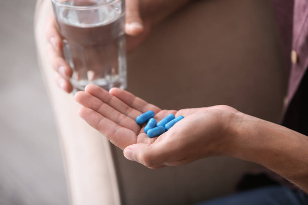 Homme tenant des pilules et un verre d'eau, gros plan
 - Photo, image