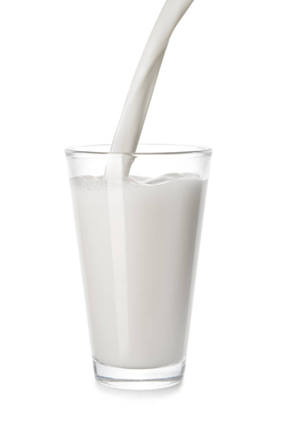 Gieten van lekkere melk in glazen op witte achtergrond - Foto, afbeelding