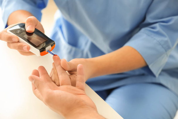 Médecin prélevant un échantillon de sang du patient diabétique à l'aide d'un glucomètre numérique, gros plan
 - Photo, image