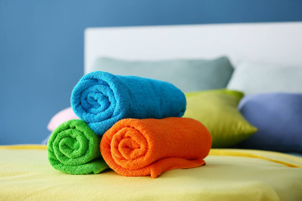 ベッドの上のきれいなテリー織りのタオルを巻いてください。 - 写真・画像