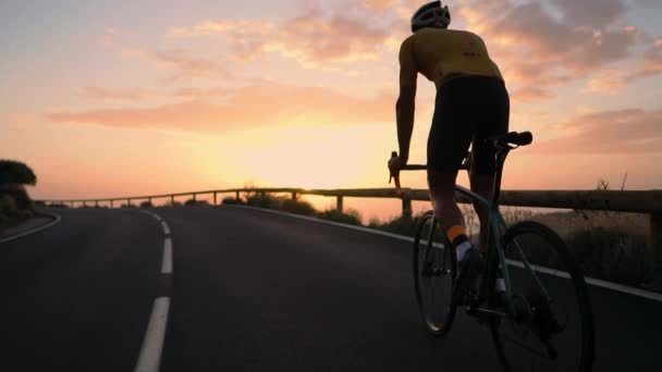 Ein junger Sportler, der mit gelbem T-Shirt-Helm und Sportausrüstung auf einem Mountainbike in Serpentine fährt. Schwebestativ in Zeitlupe - Filmmaterial, Video