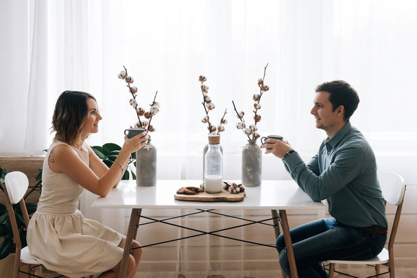 Young beautiful happy loving couple sitting at the table looking at each other. Beginning of love story. Relationship love, lifestyle concept. Couple in love on a date - Photo, image