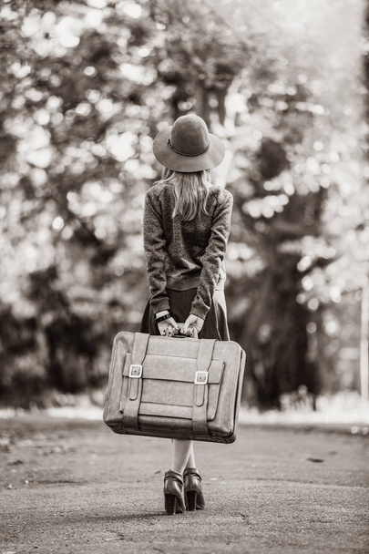 girl in hat with suitcase in the park. Image in black and white color style - Valokuva, kuva