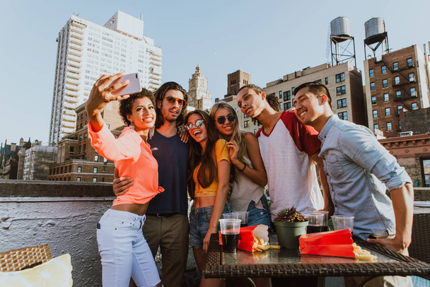 Group of friends spending time together on a rooftop in New york city, lifestyle concept with happy people - Photo, Image