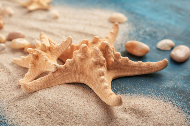Starfishes with sand on color table - Φωτογραφία, εικόνα