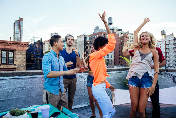 Group of friends spending time together on a rooftop in New york city, lifestyle concept with happy people - Photo, image