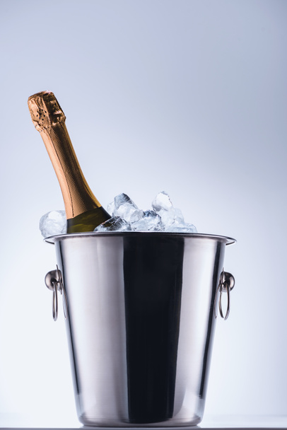 close up view of bottle of champagne in bucket with ice cubes on grey background - Photo, Image