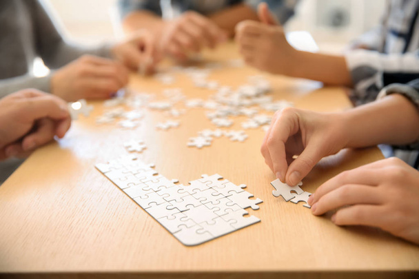 Groupe de personnes assemblant puzzle sur table en bois
 - Photo, image