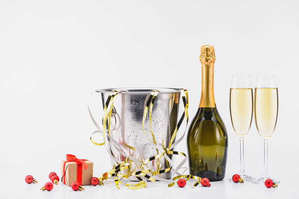 close up view of bottle of champagne, bucket with confetti, glasses of champagne and wrapped christmas gift on grey background - Photo, Image