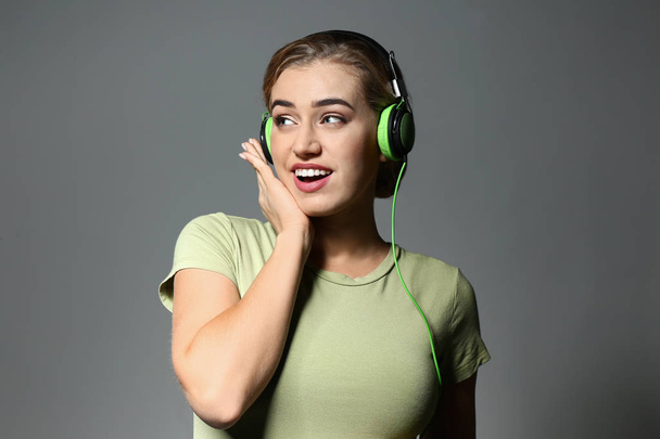 Piękna młoda kobieta, słuchanie muzyki na szarym tle - Zdjęcie, obraz