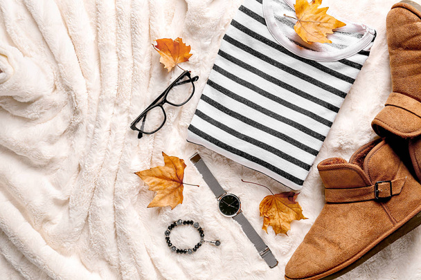 stylisches Outfit mit Accessoires und Herbstblättern auf flauschigem Stoff - Foto, Bild