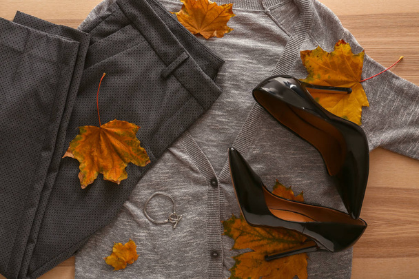 Elegante atuendo con zapatos elegantes y hojas de otoño sobre fondo de madera, vista superior
 - Foto, imagen
