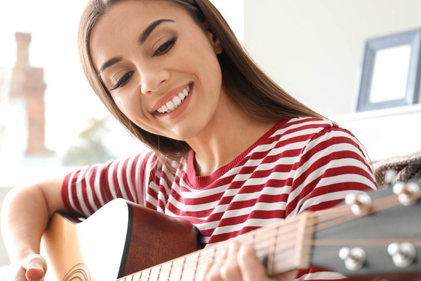 красивая женщина играет на гитаре дома
 - Фото, изображение