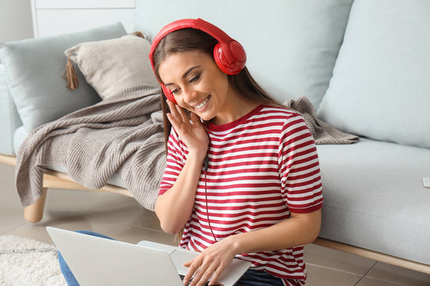 schöne Frau mit Laptop, die zu Hause Musik hört - Foto, Bild