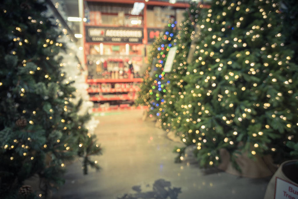 Abstract blurred artificial Christmas trees with colorful lights at hardware store in America. Xmas cheerful display decoration, home decor supplies, wreaths and strings of bokeh light - Photo, Image