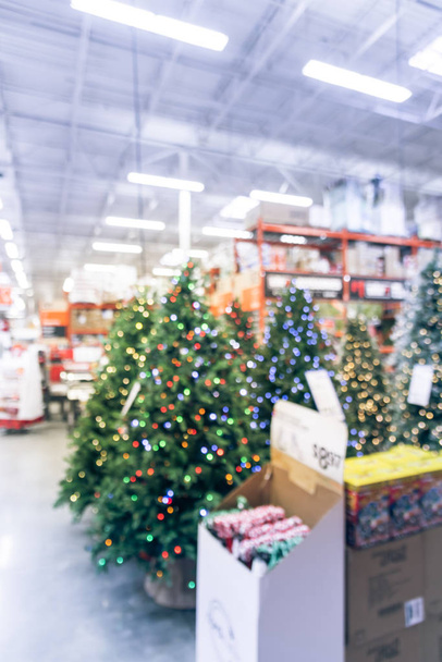 Abstraktní rozmazané umělé vánoční stromky s barevnými světly v železářství v Americe. Vánoční dekorace veselá displej, zásoby domácí výzdoba, věnce a řetězce bokeh světla - Fotografie, Obrázek