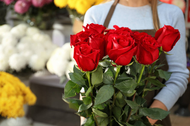 Vendedora sosteniendo ramo de hermosas rosas en la tienda
 - Foto, imagen