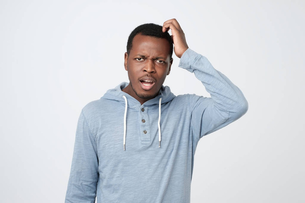 junger afrikanischer Mann in blauem Hemd denkt an kratzenden Kopf auf weißem Hintergrund - Foto, Bild