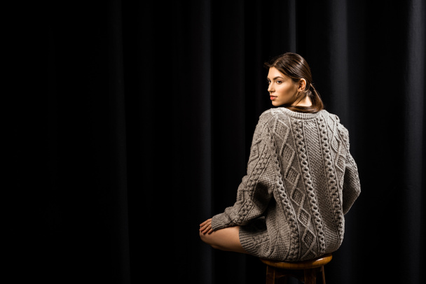attractive pensive woman in woolen grey sweater on black background - Photo, Image