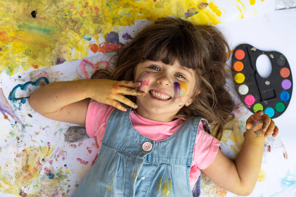 Portrait of cute kid having fun with hands paint. Funny little girl with colored face using watercolours.  - Fotoğraf, Görsel
